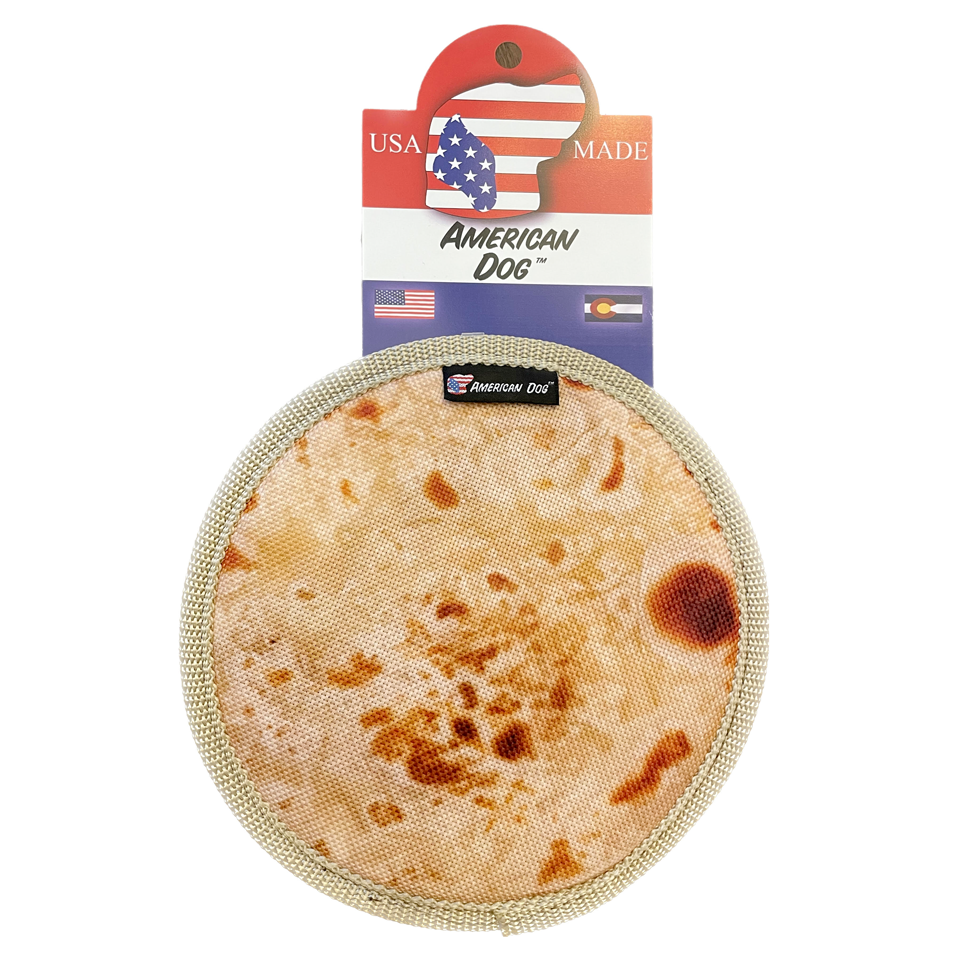 A canvas dog frisbee with a tortilla graphic printed on it lies flat on a white background, with a made in USA tag attached