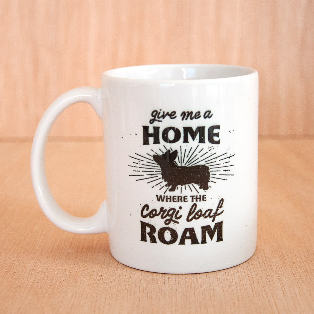white coffee mug with a black design that reads 'give me a home where the corgi loaf roam' with a graphic of a Pembroke welsh corgi dog in the center