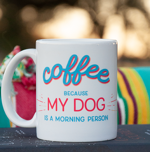 Coffee because my dog is a morning person mug sits outside on a fall morning, by a picnic blanket