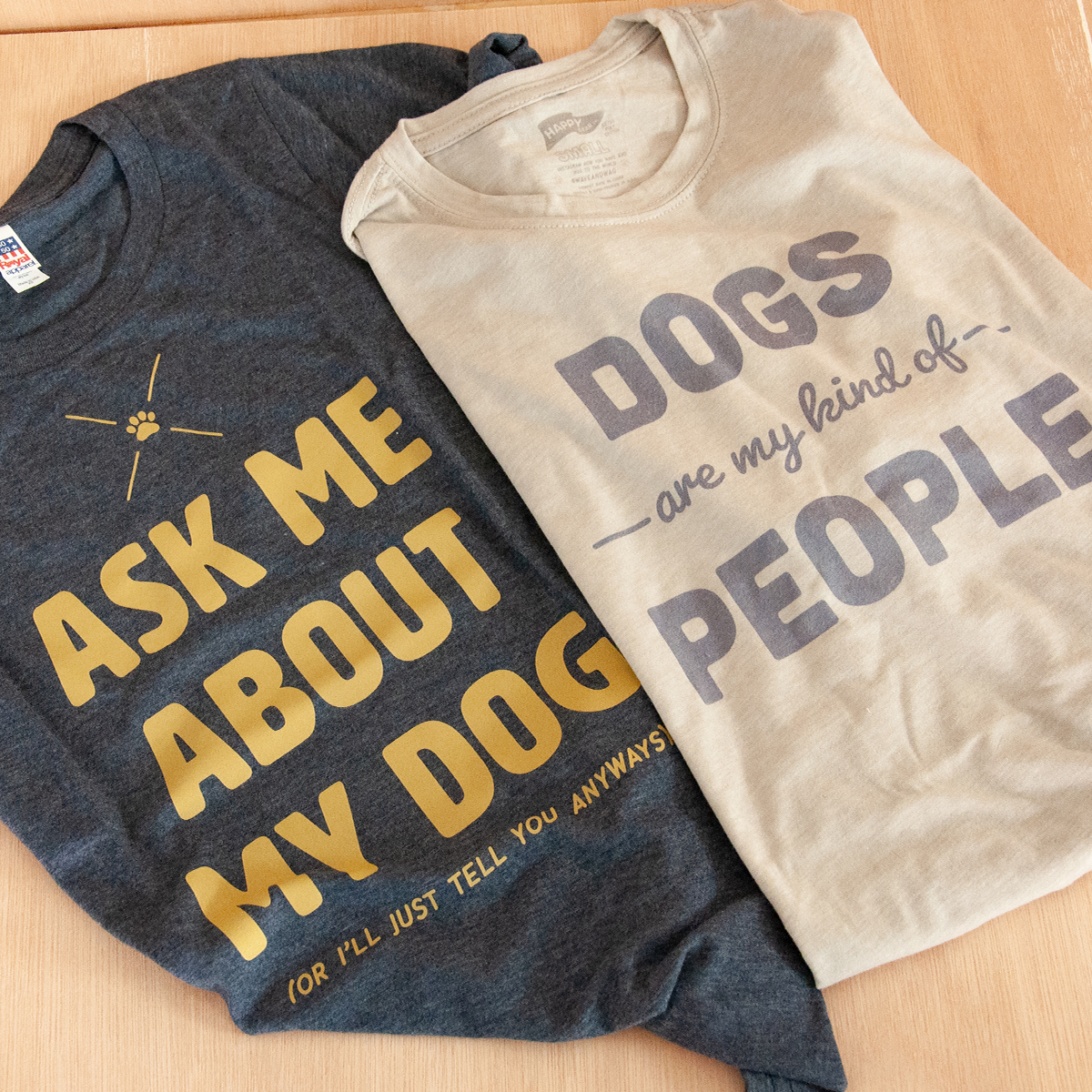 dog themed t shirts for human lay side by side, one reads Ask Me About My Dog or I'll just tell you anyways, the second says Dogs are my kind of people